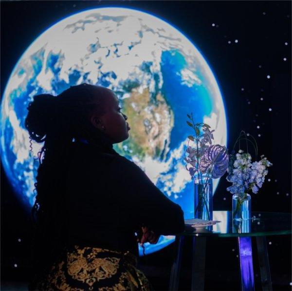 A visitor to 欧洲杯押注's "The Blue Dot Experience," event is silhouetted against an image of the Earth.